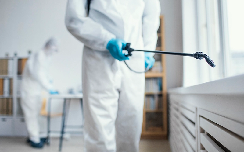 Professionals in protective gear doing indoor disinfection.