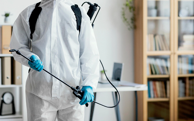 Person in protective equipment disinfecting