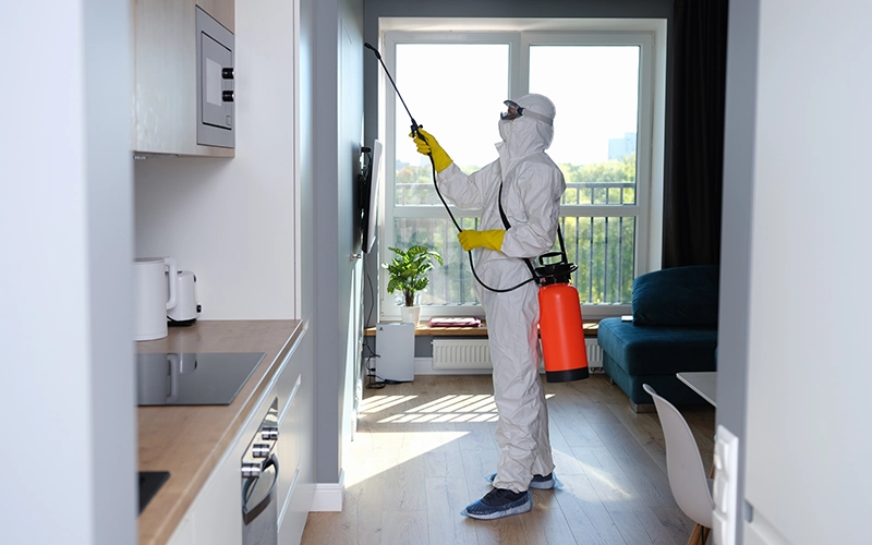 Man in protective suit treating with disinfectant flat