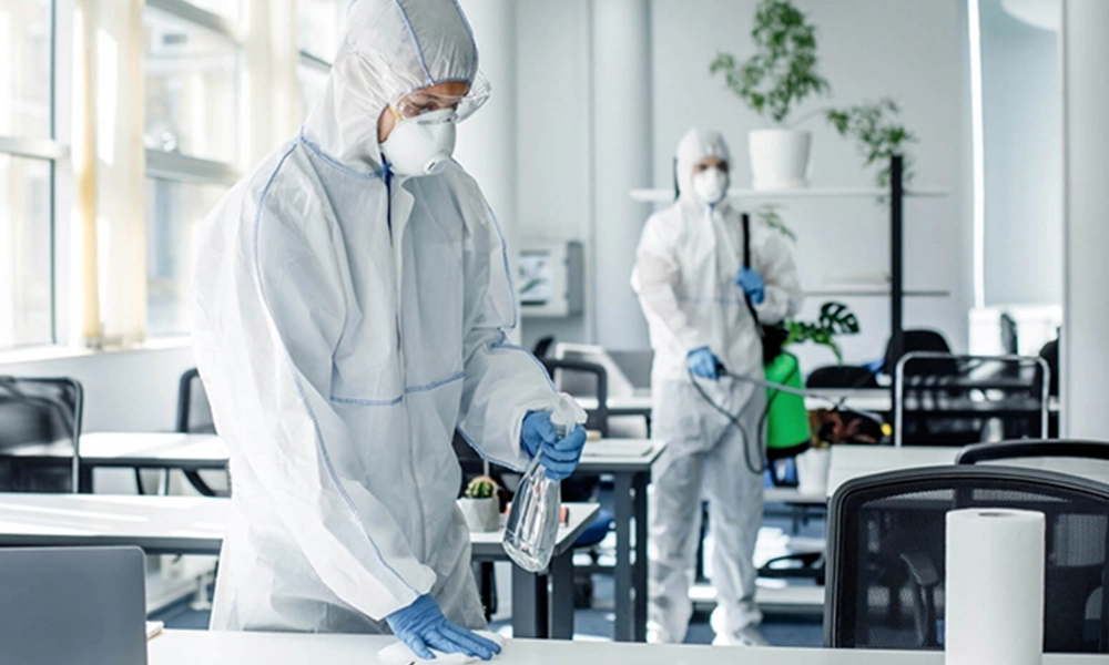Professionals in protective suits disinfecting an office space, highlighting pest prevention and sanitation measures in commercial buildings.